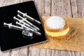 Brazilian cream donuts next by several syringes and ampoules with insulin on the tablet