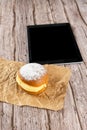 Brazilian cream doughnuts on a brown paper in the foreground. A tablet in the background