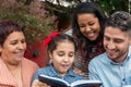 Brazilian family generations reading book together in table outside