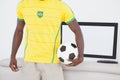 Brazilian fan holding ball in front of tv Royalty Free Stock Photo
