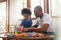 Brazilian Father and his Little son playing building tower from wooden block toy on sofa in Living room. Happy African American