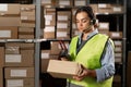female worker in headset at logistics warehouse using digital tablet. against the background of shelves with cardboard Royalty Free Stock Photo