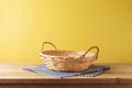 Brazilian Festa Junina summer harvest festival concept. Empty basket with tablecloth on wooden table over yellow background. Mock