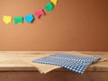 Brazilian Festa Junina summer harvest festival concept. Empty wooden table with tablecloth over wall background. Mock up for