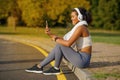 brazilian lady athlete with headphones video calling on smartphone outdoor
