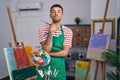 Brazilian young man holding painter palette at artist studio looking at the camera blowing a kiss being lovely and sexy Royalty Free Stock Photo