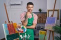 Brazilian young man holding painter palette at artist studio winking looking at the camera with sexy expression, cheerful and Royalty Free Stock Photo