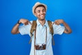 Brazilian young man holding vintage camera looking confident with smile on face, pointing oneself with fingers proud and happy Royalty Free Stock Photo