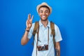 Brazilian young man holding vintage camera showing and pointing up with fingers number three while smiling confident and happy