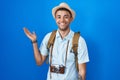 Brazilian young man holding vintage camera smiling cheerful presenting and pointing with palm of hand looking at the camera