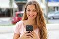 Brazilian young woman walking in the city sending text message on smartphone Royalty Free Stock Photo