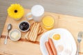 Breakfast with latte coffee, juice, toasts, jam, butter, scrambled eggs, sausages and yellow gerbera flower on wooden table Royalty Free Stock Photo