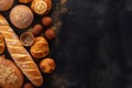 Bread, buns, loaves, rolls on rustic black wooden background, fresh breads on bakery board table counter, copy space, top view