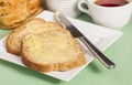 Bread and butter on square white plate and cup of herbal tea