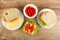 Bread and cheese, bowl with pepper, sandwiches with cheese, lettuce, sweet pepper on table. Top view