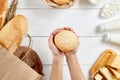 Bread in ecology paper bag. Natural organic food: milk, cheese and bakery. Zero waste recycling. Female hands gives bun Royalty Free Stock Photo