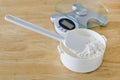 Bread flour in white bowl with rubber scraper and scale on wood