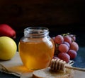 Bread with honey on paper, ripe grapes, nuts and apples on a dark background Royalty Free Stock Photo