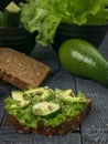 Bread with lettuce, cucumber and avocado on a wooden table Royalty Free Stock Photo