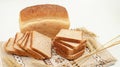 Bread loaf with multiple sliced pieces placed on rustic fabric with wheat grains creating a natural warm bakery themed composition Royalty Free Stock Photo