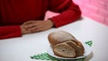 Bread lying on plate, woman sitting at table, refusing to eat high calorie food