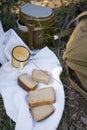 Bread, military flask, iron mug lie on a white towel