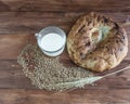 Still life of baked lavash, wheat ears, grains and mugs of milk.