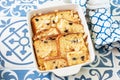 Bread panettone pudding from leftovers with custard and raisins in a baking dish on a blue background