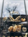 Bread in a restaurant window. Reflection of trees in a glass window.