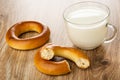 Bread rings baranka, broken baranka, cup with milk on table Royalty Free Stock Photo