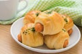 Bread roll with sausage on plate and coffee cup