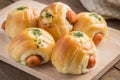 Bread roll with sausage on wooden plate