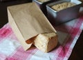 Bread on a rye ferment without yeast in a paper bag on a checkered tablecloth. Loaves in baking forms in the background Royalty Free Stock Photo