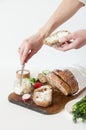 Bread with salt, butter, cucumber and radishes lie on a white background. A girl is buttering a sandwich.