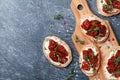 Bread slices with cream cheese and sun dried tomatoes on wooden table top view. Delicious snack and appetizer. Royalty Free Stock Photo