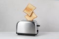 Bread slices popping up from toaster on white wooden table Royalty Free Stock Photo