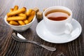 Bread sticks in bowl, sugar, teaspoon, tea in cup on saucer on t