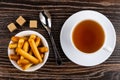 Bread sticks in bowl, teaspoon, sugar, tea in cup on saucer on t