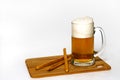 Bread sticks and misted mug of beer on a wooden cutting board. Foam and drops