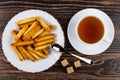 Bread sticks in plate, teaspoon, sugar, tea in cup on saucer on