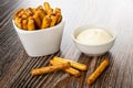 Bread sticks with poppy in white bowl, bowl with mayonnaise, breadsticks on wooden table