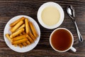 Bread sticks in saucer, bowl with condensed milk, teaspoon, tea Royalty Free Stock Photo