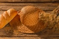Bread, straw hat and wheat spikelets on wooden background. Royalty Free Stock Photo