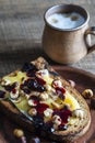Bread toast with butter, roasted hazelnuts, honey, berry jam on plate and cappuccino coffee in a clay cup on wooden table, closeup Royalty Free Stock Photo