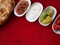 Bread, vegetables, sauces and snacks in plates on a red tablecloth, top view with empty copy space, background for menu Royalty Free Stock Photo