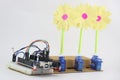 Breadboard circuit with programmable controller board and micro servo with artificial flowers attached to horn of servos