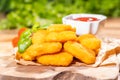 Breaded chicken nuggets with ketchup and lettuce on a wooden kitchen board. Fast food