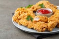 Breaded chicken strips with tomato ketchup on a white plate. Fast food on dark brown background Royalty Free Stock Photo