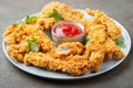 Breaded chicken strips with tomato ketchup on a white plate. Fast food on dark brown background Royalty Free Stock Photo