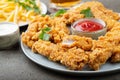 Breaded chicken strips with tomato ketchup on a white plate. Fast food on dark brown background Royalty Free Stock Photo